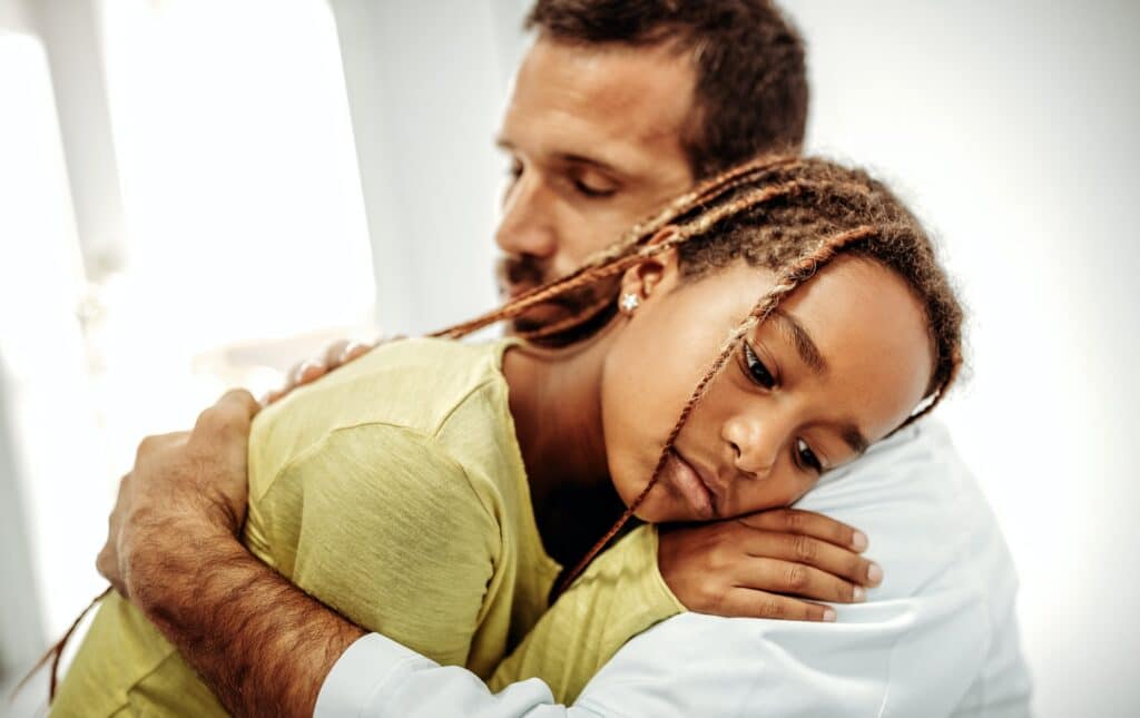 Doctor having conversation with sad little girl at the hospital. Doctor consoling child