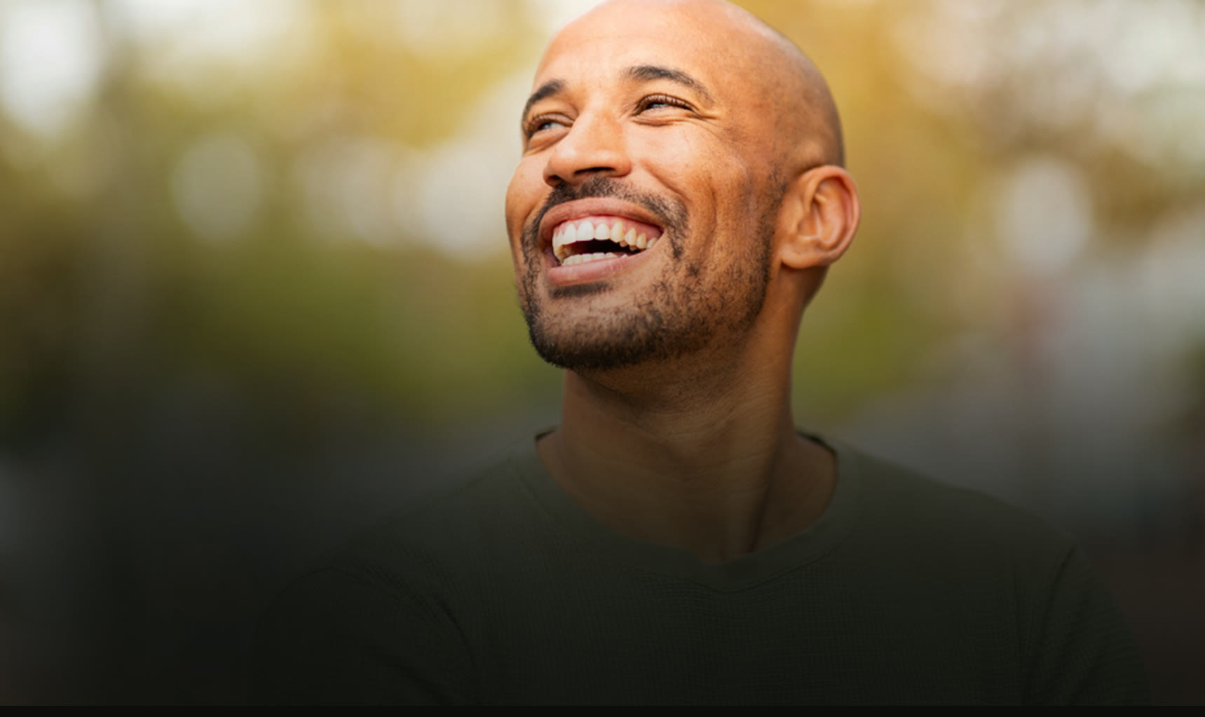 Smiling bald man looking upward outdoors