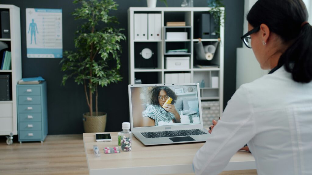 A clinician talking with a patient via video call on a laptop