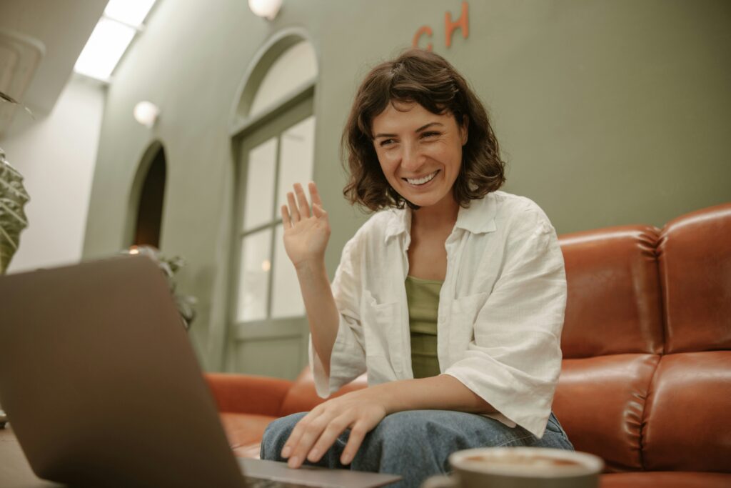 A lady sitting on a couch using a laptop for a video call