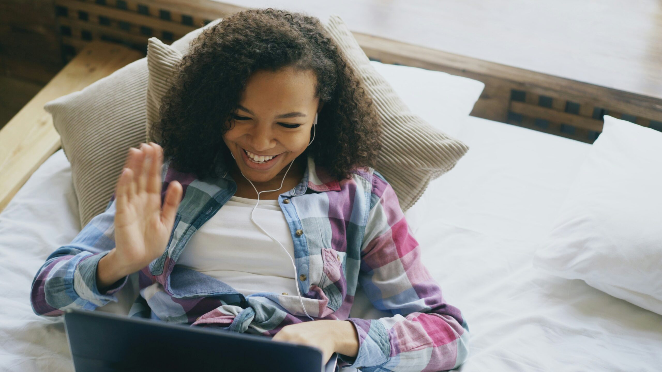 Happy young woman lying on a bed while on a video call