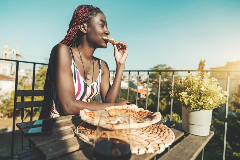 Black girl eating, outdoor pizzeria